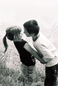 Young boy leans in to kiss young girl